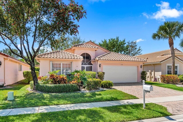 mediterranean / spanish-style house with stucco siding, a front lawn, driveway, a tile roof, and an attached garage