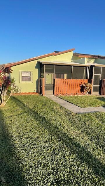 1732 W Sanderling Ln Unit 1, Fort Pierce, FL 34982 - rear view of house featuring a sunroom, stucco siding, and a lawn
