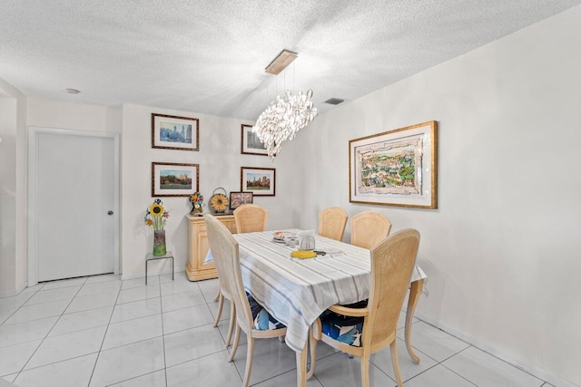 dining space featuring light tile patterned floors, visible vents, a textured ceiling, and an inviting chandelier