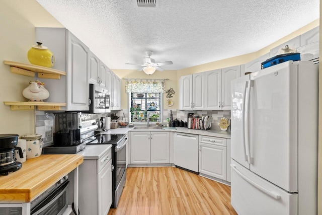 kitchen featuring light wood-style floors, stainless steel appliances, tasteful backsplash, and light countertops