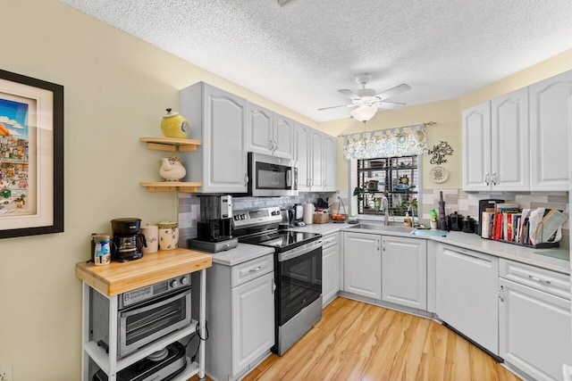 kitchen featuring open shelves, stainless steel appliances, backsplash, and light countertops