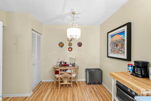 dining space featuring electric panel, baseboards, light wood-style floors, and a textured ceiling