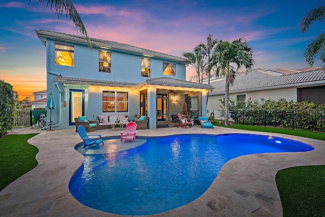 back of house at dusk with a tile roof, a fenced backyard, outdoor lounge area, and a patio area