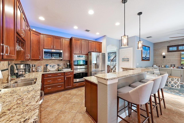 kitchen with a breakfast bar, a sink, backsplash, stainless steel appliances, and arched walkways