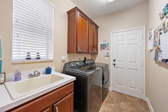 laundry room featuring washer and clothes dryer, light tile patterned floors, cabinet space, a textured ceiling, and a sink