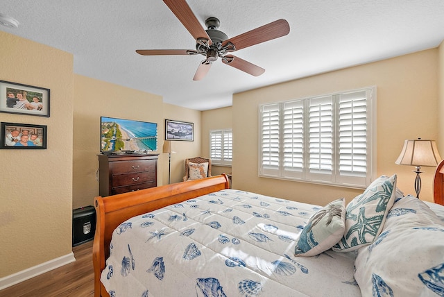 bedroom with a ceiling fan, wood finished floors, baseboards, and a textured ceiling