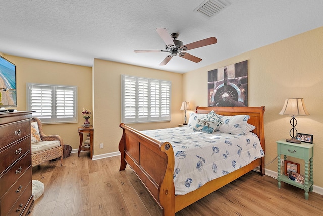 bedroom with visible vents, baseboards, a textured ceiling, and light wood-style flooring