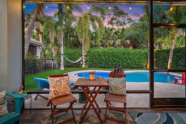 pool at dusk featuring a fenced in pool, a patio, and a fenced backyard