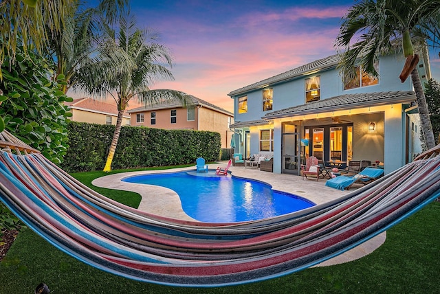 pool at dusk featuring a patio area, a fenced in pool, and a fenced backyard