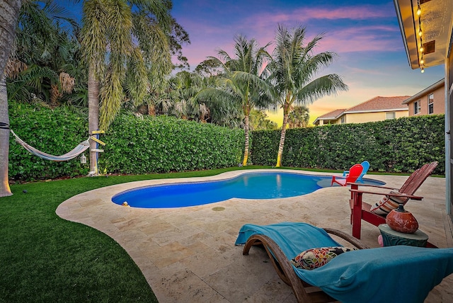 pool at dusk with a fenced backyard, a fenced in pool, a lawn, and a patio