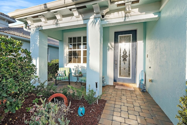 view of exterior entry with covered porch and stucco siding