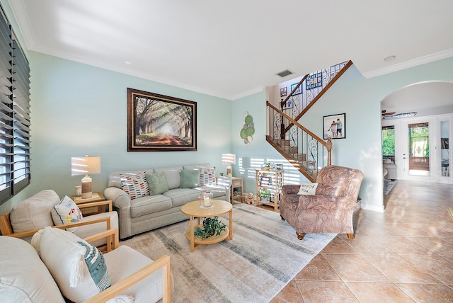 tiled living area with visible vents, arched walkways, crown molding, and stairway