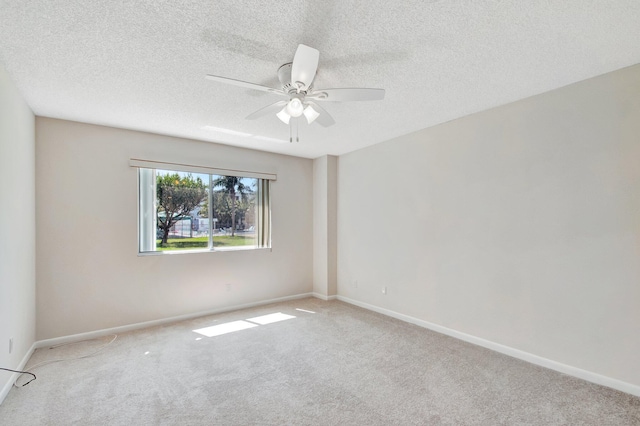 spare room with ceiling fan, a textured ceiling, baseboards, and carpet