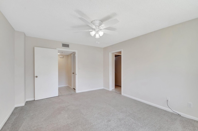 unfurnished bedroom with light carpet, visible vents, a ceiling fan, and baseboards