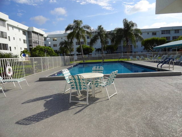 pool with a patio area and fence