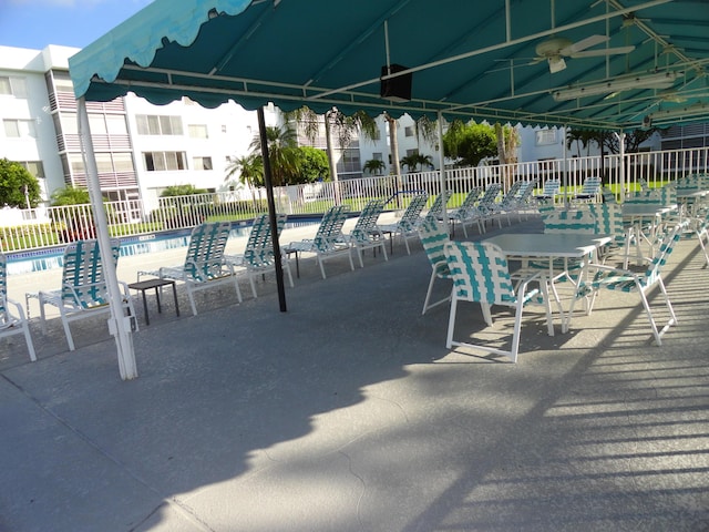 view of patio with a community pool and fence