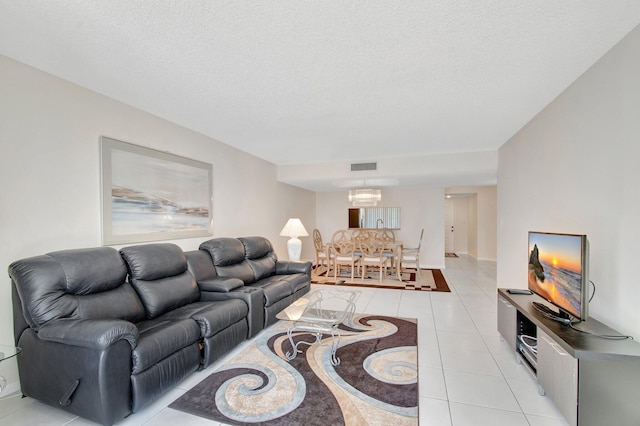 living room featuring light tile patterned floors, visible vents, a textured ceiling, and an inviting chandelier