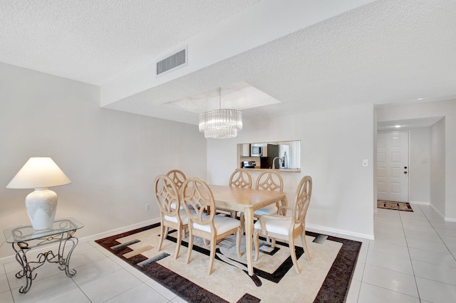 dining area featuring baseboards, visible vents, light tile patterned flooring, a textured ceiling, and a notable chandelier