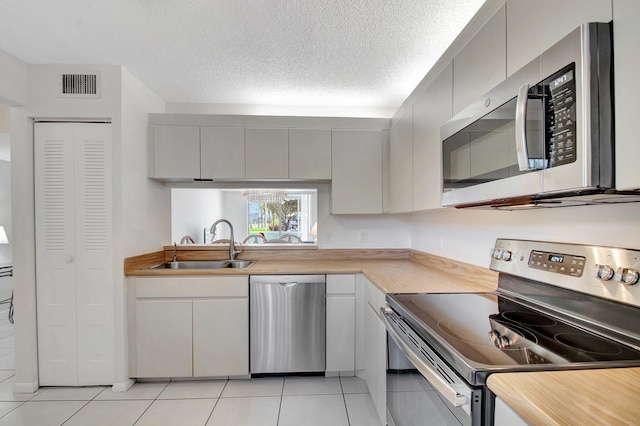 kitchen featuring visible vents, a sink, a textured ceiling, appliances with stainless steel finishes, and light countertops