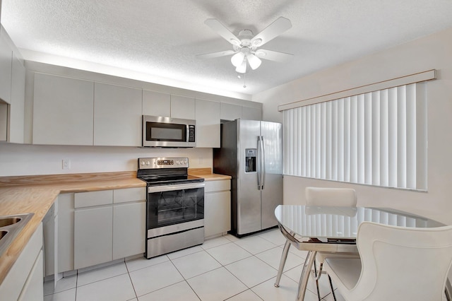 kitchen with a textured ceiling, stainless steel appliances, light countertops, and a ceiling fan