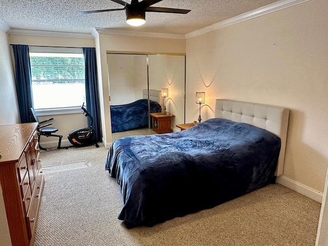 carpeted bedroom featuring a textured ceiling, a closet, crown molding, baseboards, and ceiling fan