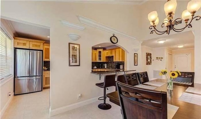 dining space featuring arched walkways, a chandelier, crown molding, and baseboards