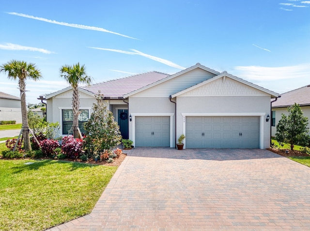 ranch-style house with stucco siding, a garage, a front lawn, and decorative driveway