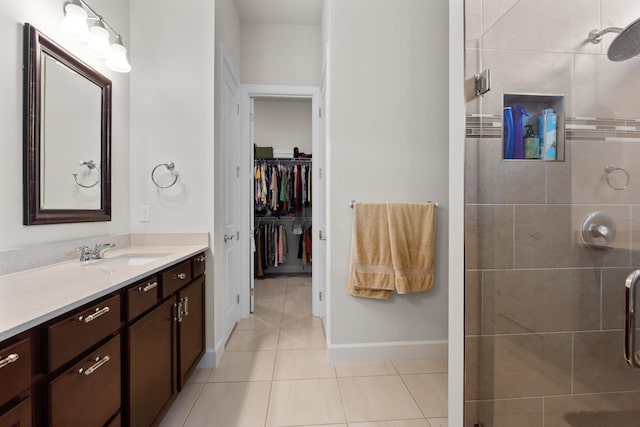 bathroom with tile patterned floors, vanity, a stall shower, and baseboards
