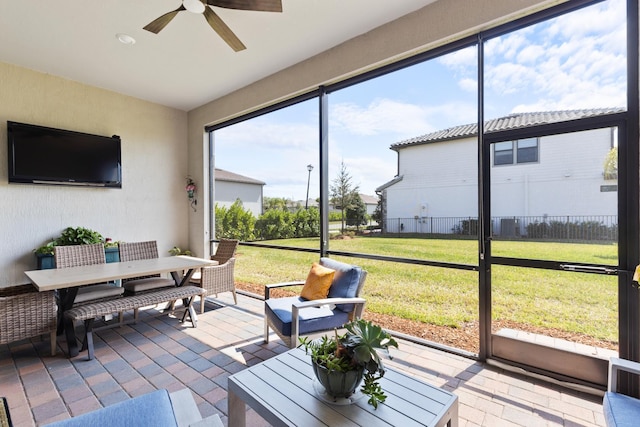 sunroom with outdoor dining area and ceiling fan