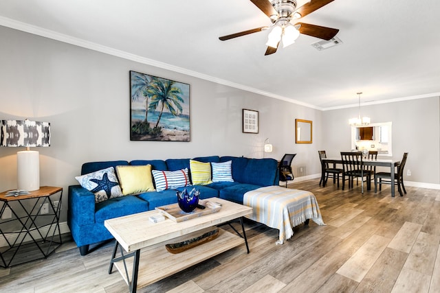 living room featuring baseboards, visible vents, ornamental molding, ceiling fan with notable chandelier, and light wood-type flooring