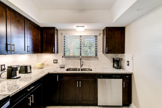 kitchen featuring light stone countertops, a sink, dark brown cabinetry, dishwasher, and tasteful backsplash