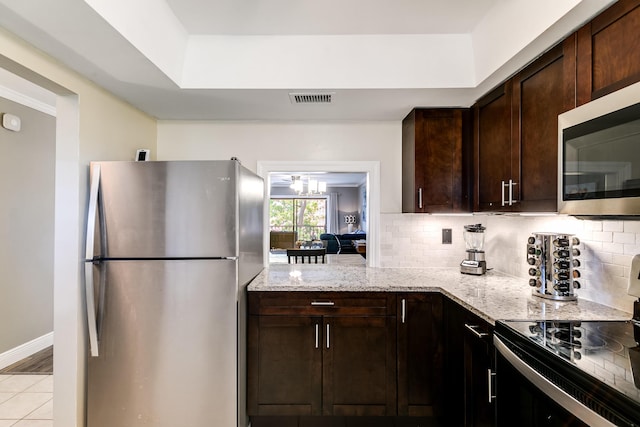 kitchen featuring light stone counters, visible vents, stainless steel appliances, decorative backsplash, and dark brown cabinets