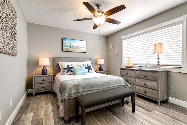 bedroom featuring baseboards, light wood-style flooring, and a ceiling fan