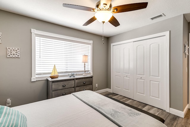 bedroom with visible vents, baseboards, a closet, and wood finished floors