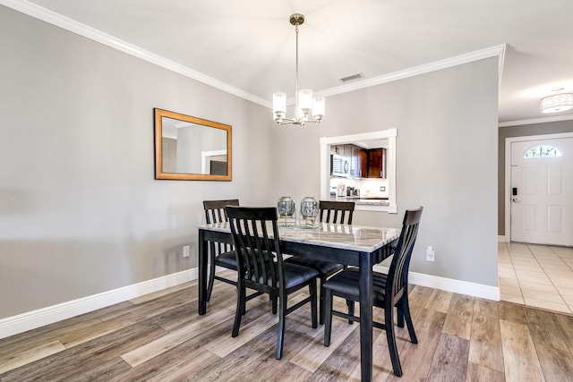 dining room featuring visible vents, crown molding, baseboards, an inviting chandelier, and wood finished floors