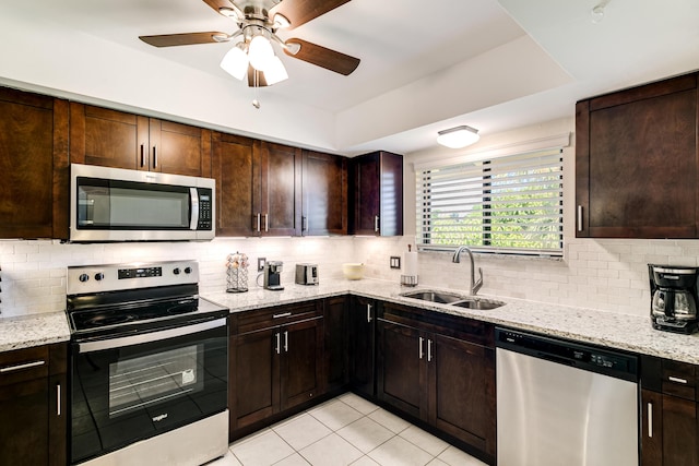 kitchen with decorative backsplash, light stone countertops, stainless steel appliances, and a sink