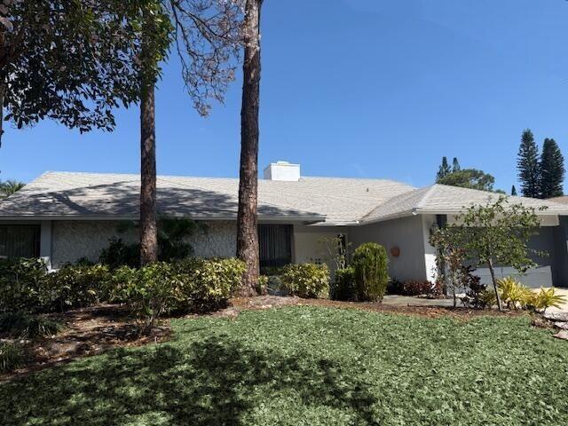 view of front of property featuring stucco siding, a front lawn, and a garage