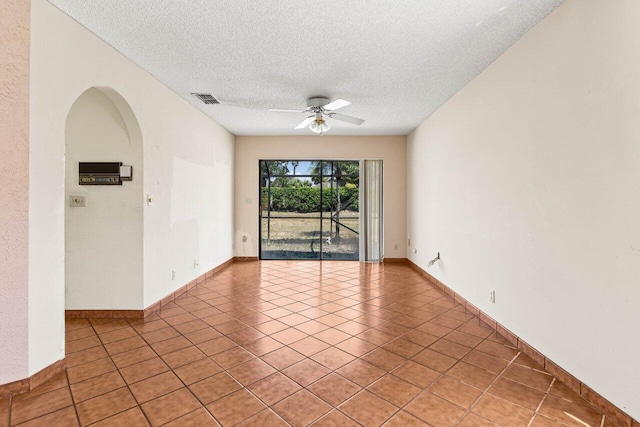 empty room with a textured ceiling, light tile patterned floors, a ceiling fan, and visible vents