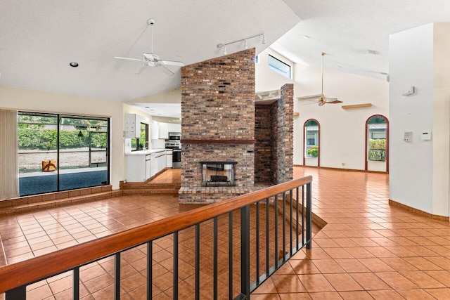 unfurnished living room with light tile patterned floors, ceiling fan, rail lighting, and a fireplace