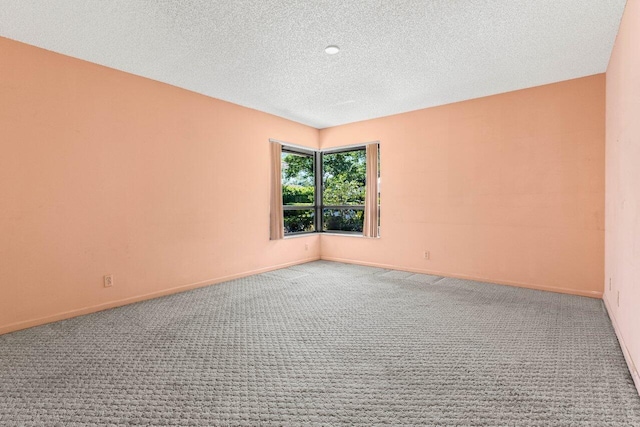 carpeted empty room featuring baseboards and a textured ceiling