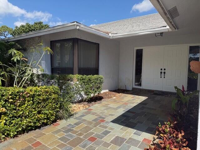 entrance to property featuring stucco siding and a patio area