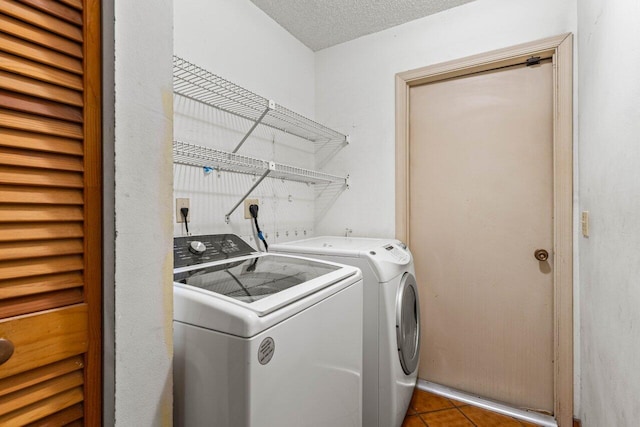 laundry room featuring laundry area, tile patterned flooring, washing machine and dryer, and a textured ceiling