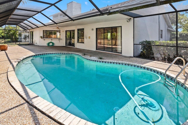 outdoor pool with a patio, glass enclosure, and a ceiling fan