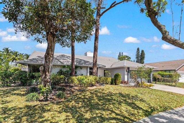 single story home featuring an attached garage, a chimney, concrete driveway, and a front lawn
