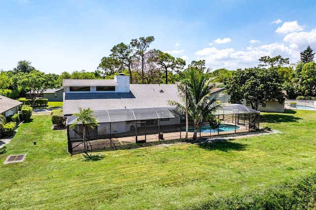 back of property with a lanai, an outdoor pool, a chimney, and a yard
