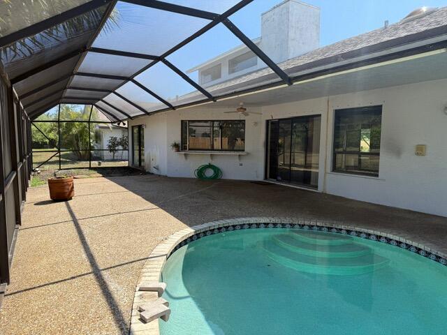 pool featuring a lanai, a patio area, and ceiling fan