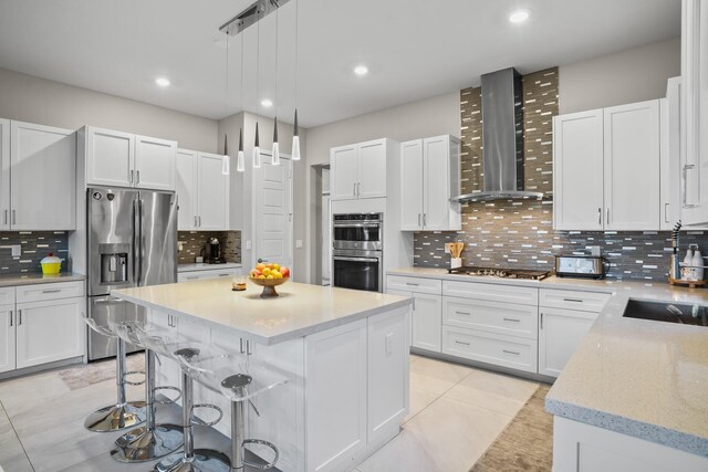 kitchen featuring decorative backsplash, wall chimney exhaust hood, a kitchen island, and stainless steel appliances