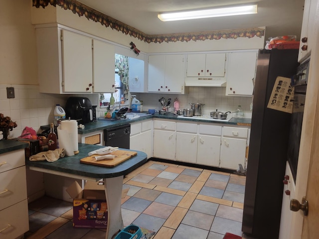 kitchen with dark countertops, under cabinet range hood, white stovetop, black dishwasher, and a sink