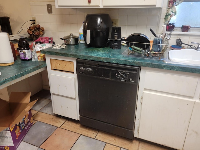 kitchen with dark countertops, black dishwasher, decorative backsplash, white cabinetry, and a sink