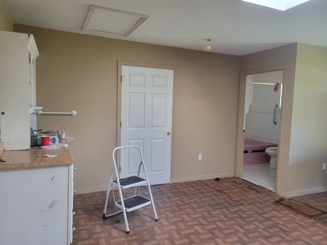 interior space with butcher block countertops, white cabinetry, and baseboards